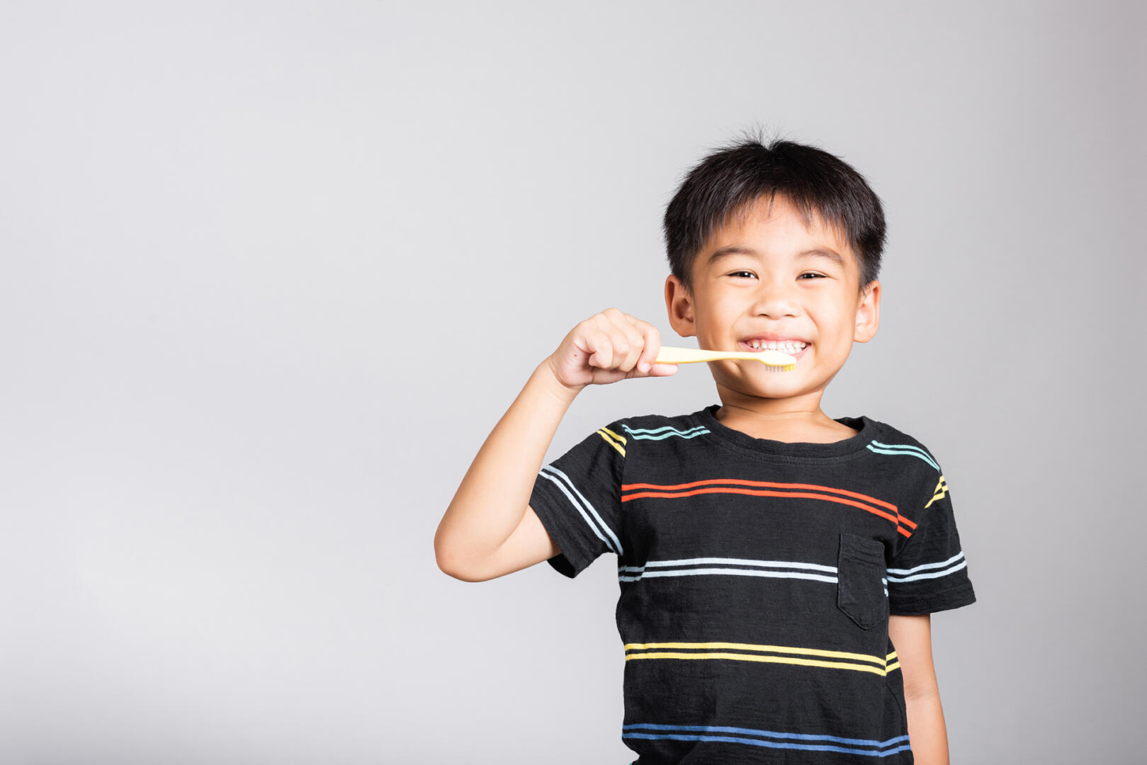 Little cute kid boy 5 6 years old brushing teeth and smile in studio shot isolated